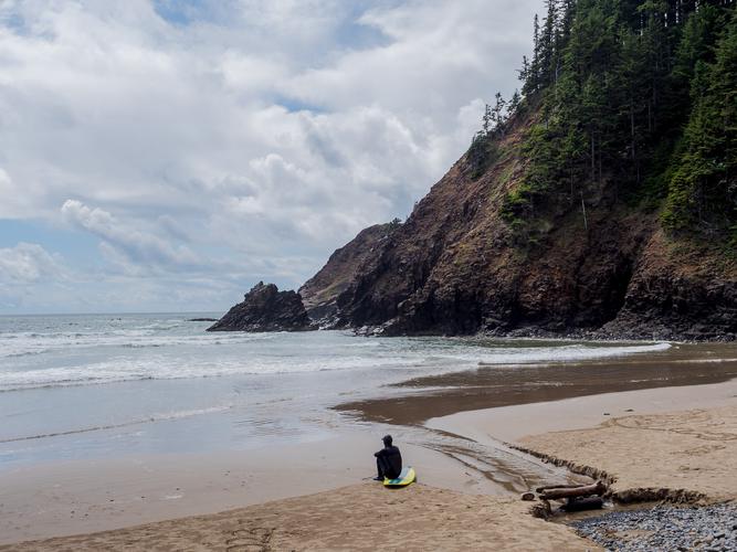 Серфер сидит на доске на пляже