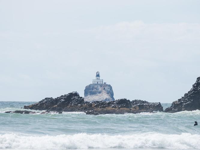 Вид на маяк на скале с пляжа