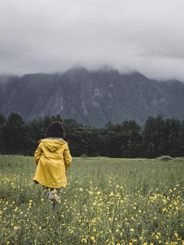 Девушка в желтой куртке на фоне туманных гор
