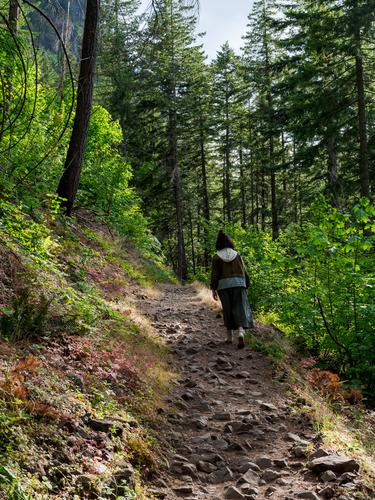 Девушка поднимается по тропинке вдоль горного склона
