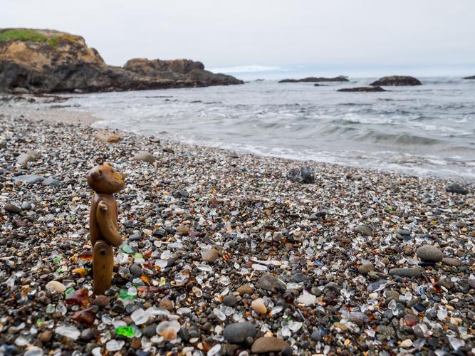 Beach with glass among stones and a toy bear Beach with glass among stones and a toy bear