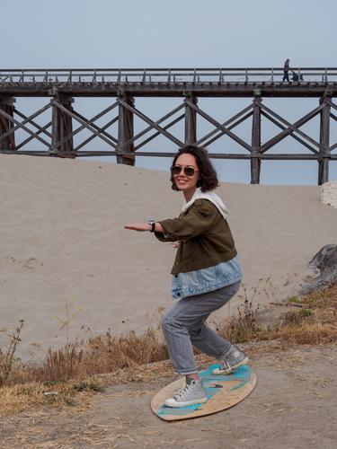 Девушка стоит на доске для серфинга на песке