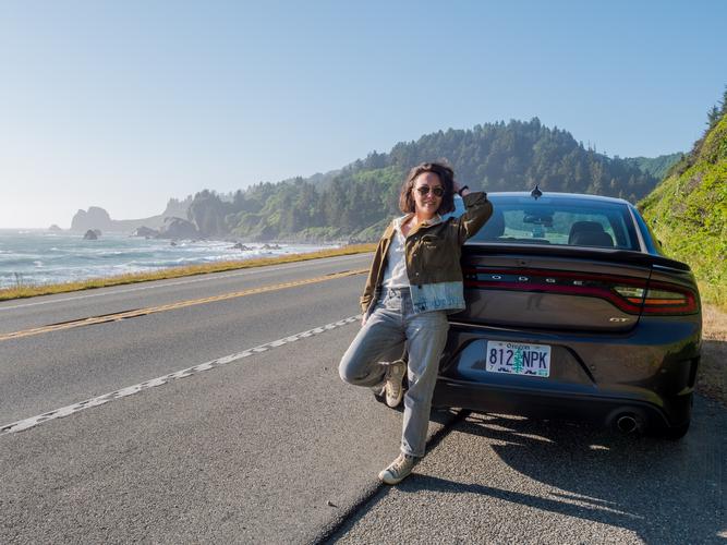 Девушка стоит облокотившись на автомобиль