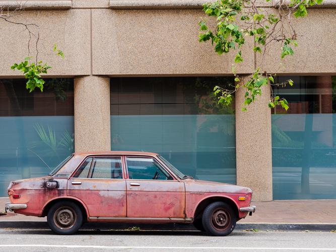 Красная машина на фоне серой стены