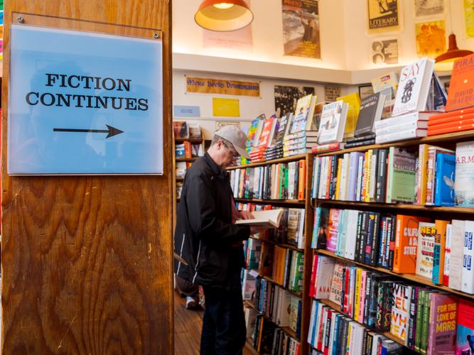 Мужчина смотрит на полку в книжном магазине